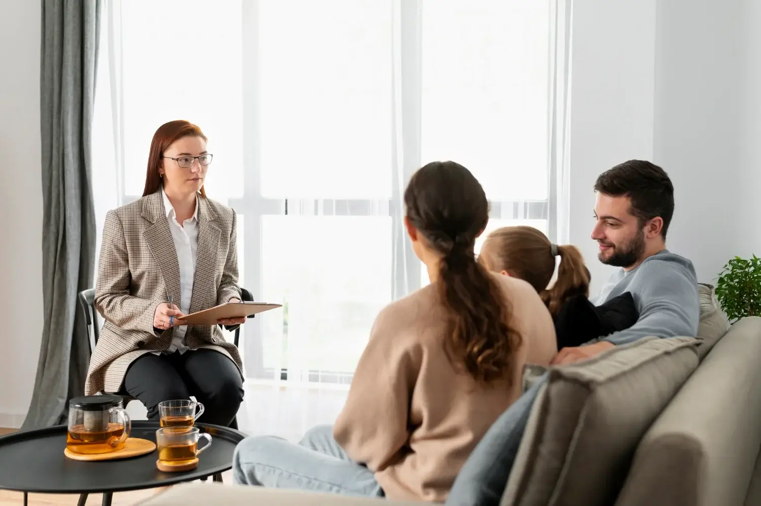 Therapist speaking with a family on a couch during a warm, supportive counselling session.